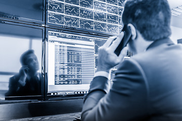 Image showing Stock trader looking at market data on computer screens.