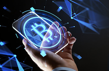 Image showing close up of hand with smartphone and bitcoin