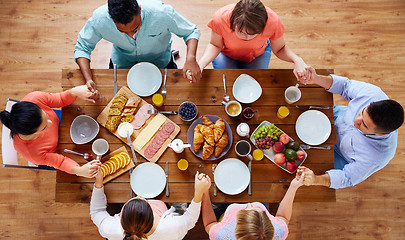 Image showing group of people at table praying before meal