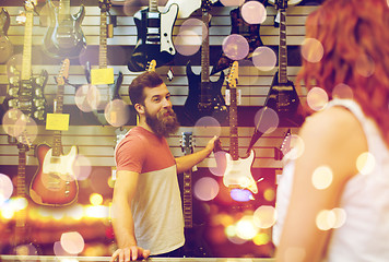 Image showing assistant showing customer guitar at music store