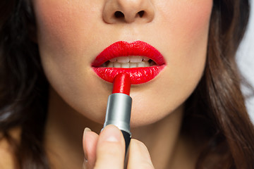 Image showing close up of woman applying red lipstick to lips