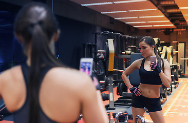 Image showing woman with smartphone taking mirror selfie in gym