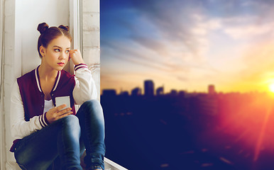 Image showing teenage girl sitting on windowsill with smartphone