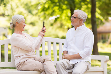 Image showing old woman photographing man by smartphone in park