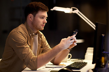 Image showing man with smartphone working late at night office