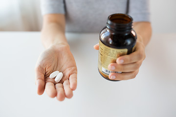 Image showing close up of hands holding medicine pills and jar