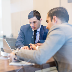 Image showing Two young businessmen using laptop computer at business meeting.