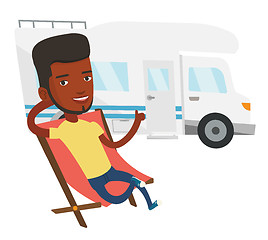 Image showing Man sitting in chair in front of camper van.