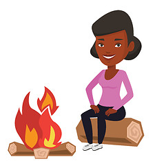 Image showing Woman sitting on log near campfire in the camping.