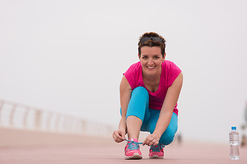 Image showing Young woman tying shoelaces on sneakers