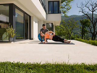 Image showing woman with personal trainer doing morning yoga exercises