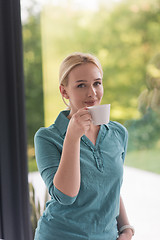 Image showing young woman drinking morning coffee by the window