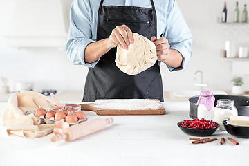 Image showing A cook with eggs on a rustic kitchen against the background of men\'s hands