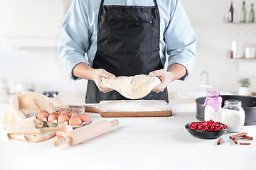 Image showing A cook with eggs on a rustic kitchen against the background of men\'s hands