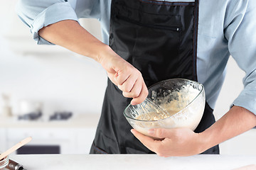 Image showing A cook with eggs on a rustic kitchen against the background of men\'s hands