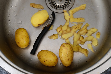 Image showing vegetable peeler, potatoes and potato peelings in the sink