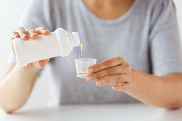 Image showing woman pouring syrup from bottle to medicine cup