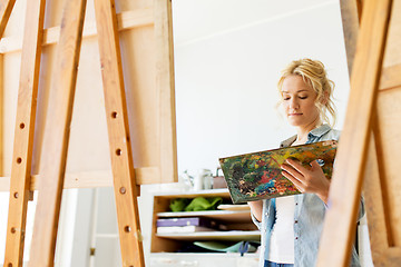 Image showing woman with easel painting at art school studio