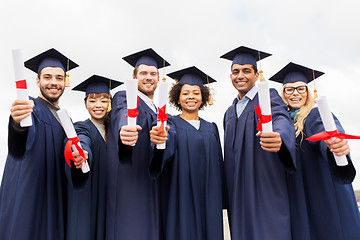 Image showing happy students in mortar boards with diplomas