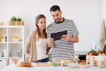 Image showing happy couple with tablet pc cooking food at home