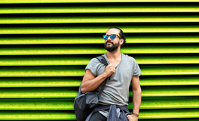 Image showing man in sunglasses with bag standing at street wall