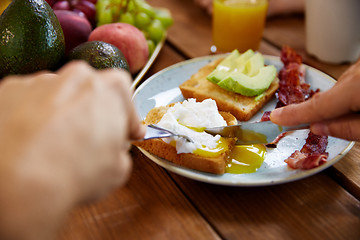 Image showing man eating toast with pouched egg and bacon