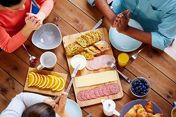 Image showing group of people at table praying before meal