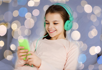 Image showing girl in headphones with smartphone over lights