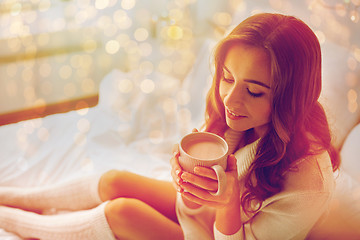 Image showing happy woman with cup of cocoa in bed at home