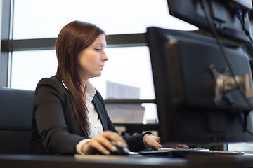 Image showing Casual businesswoman working in office, sitting at desk, typing on keyboard, looking at computer screen.