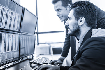 Image showing Stock traders looking at market data on computer screens.