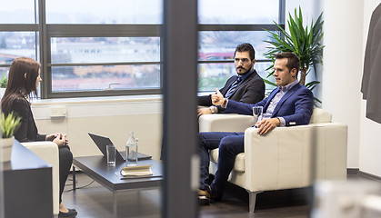 Image showing Businessmen interviewing female candidate for job in modern corporate office.