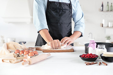 Image showing A cook with eggs on a rustic kitchen against the background of men\'s hands