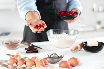 Image showing A cook with eggs on a rustic kitchen against the background of men\'s hands