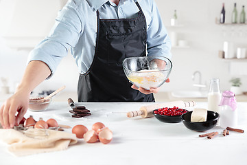 Image showing A cook with eggs on a rustic kitchen against the background of men\'s hands