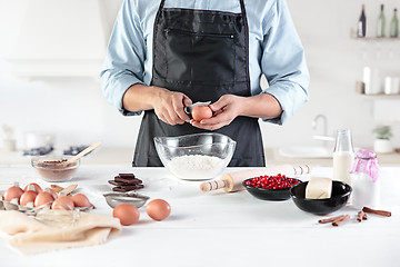 Image showing A cook with eggs on a rustic kitchen against the background of men\'s hands