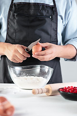 Image showing A cook with eggs on a rustic kitchen against the background of men\'s hands