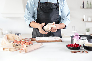 Image showing A cook with eggs on a rustic kitchen against the background of men\'s hands