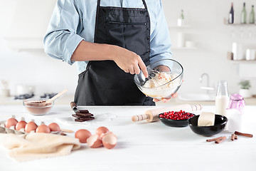 Image showing A cook with eggs on a rustic kitchen against the background of men\'s hands