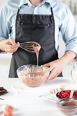 Image showing A cook with eggs on a rustic kitchen against the background of men\'s hands