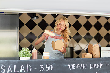 Image showing happy saleswoman making wok at food truck