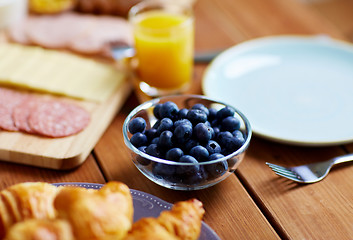 Image showing bowl of blueberries on wooden table at breakfast