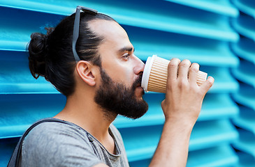 Image showing man drinking coffee from paper cup over wall