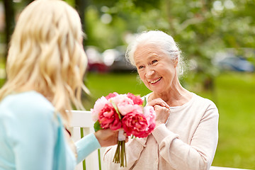 Image showing daughter giving flowers to senior mother at park
