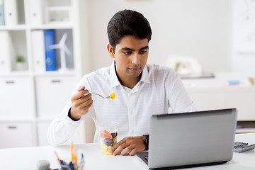 Image showing businessman with laptop eating fruits at office