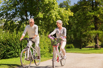 Image showing happy senior couple riding bicycles at summer park