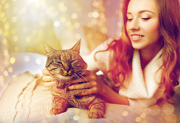 Image showing happy young woman with cat lying in bed at home