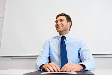 Image showing smiling young businessman sitting at office table