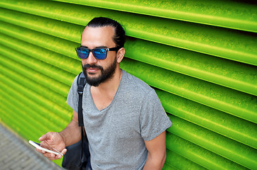 Image showing man in sunglasses with smartphone and bag at wall