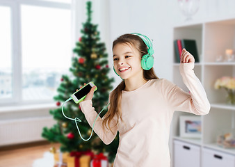 Image showing girl with smartphone and headphones at christmas